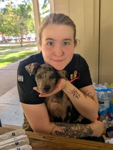 Planned PEThood staff member holding a brindle puppy at the community vaccine clinic in Winterville.